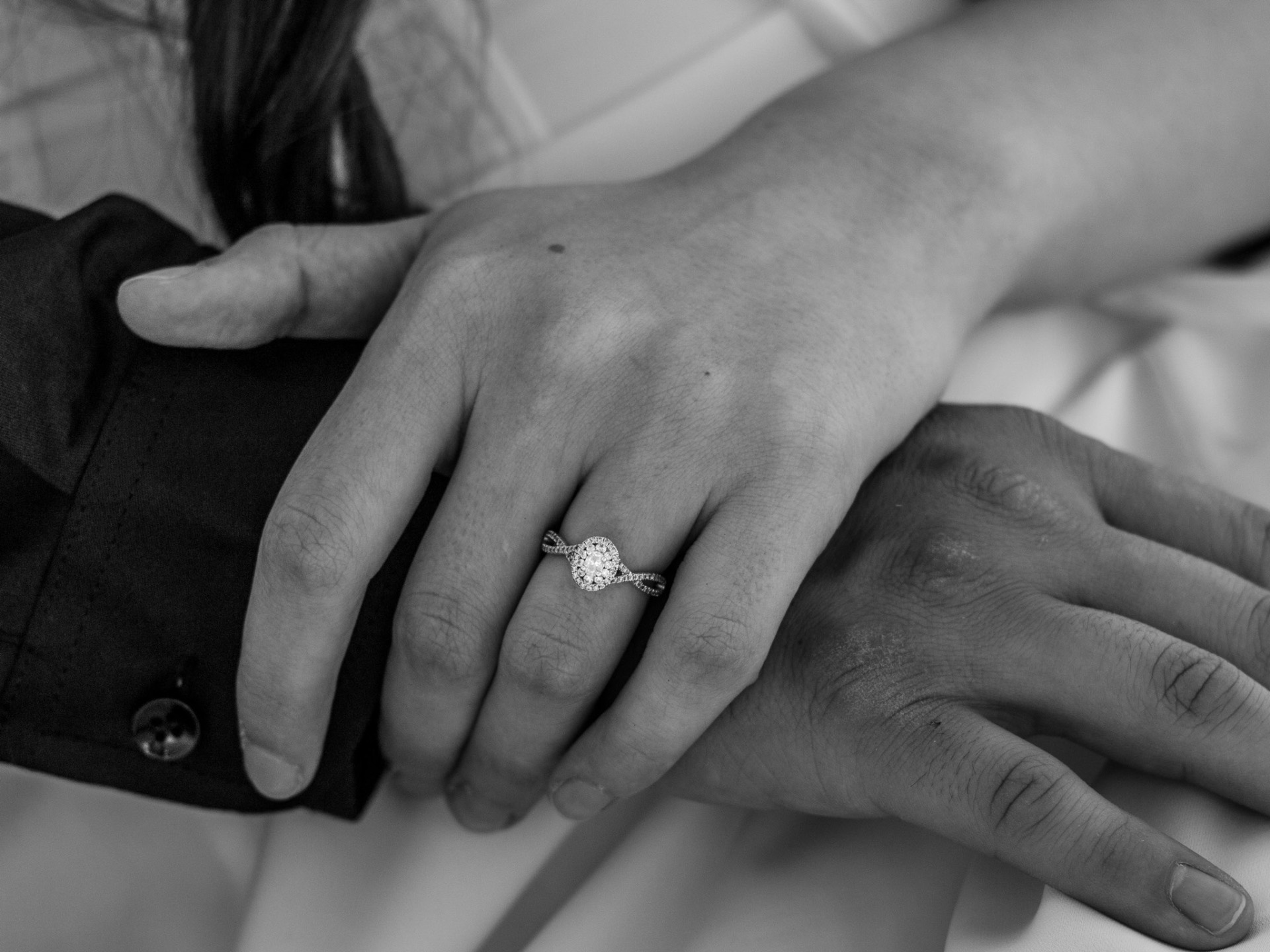 Black and white close-up of engagement ring on couple's hands