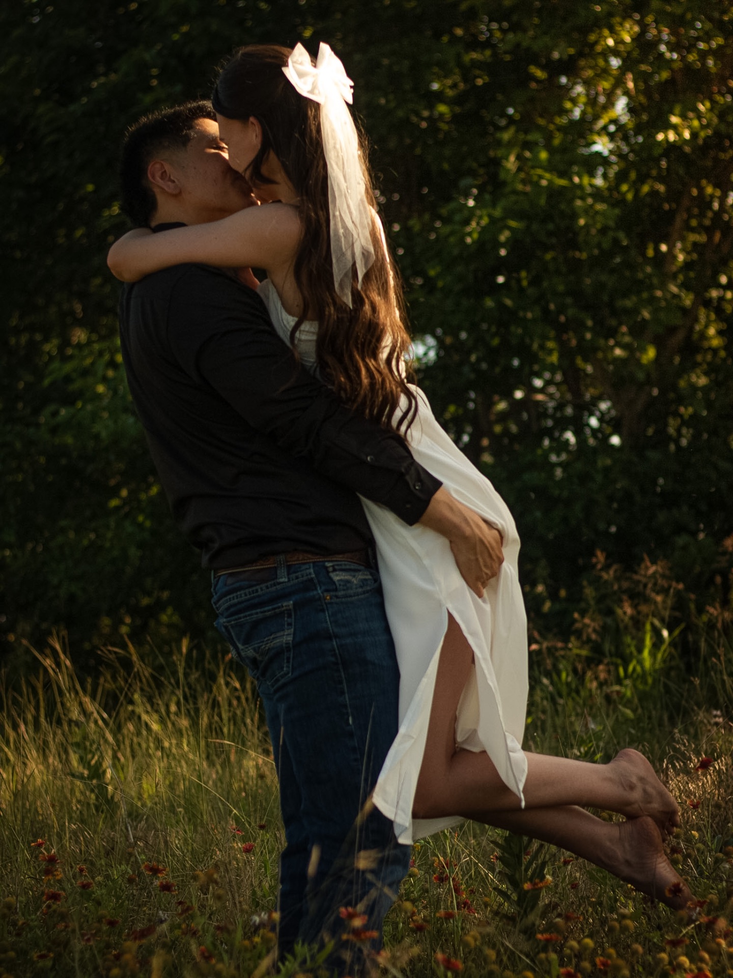 Groom lifting bride for a kiss in wildflowers