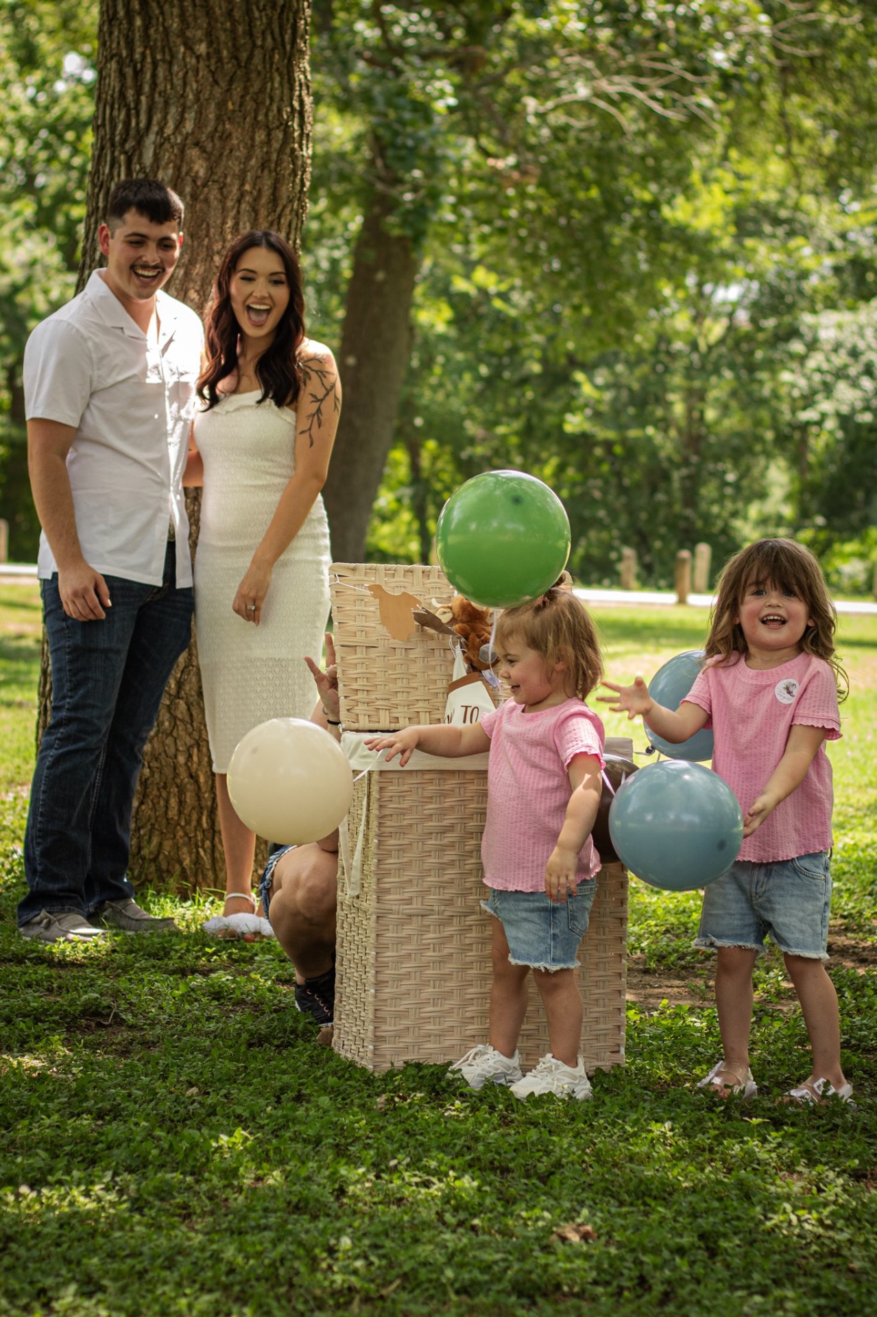 Family laughing with toddlers and balloons at a joyful baby announcement