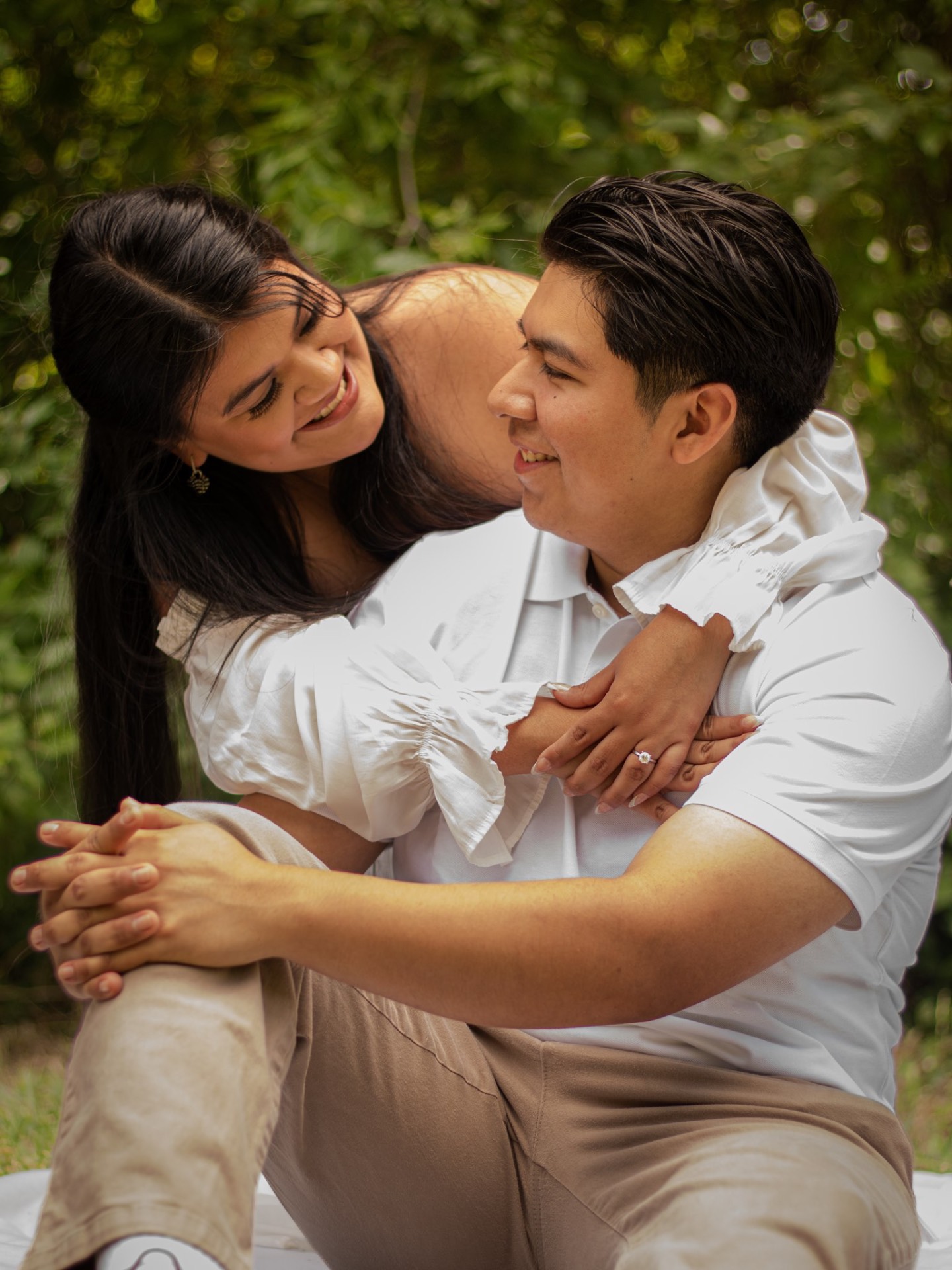 Engaged couple laughing forehead to forehead outdoors